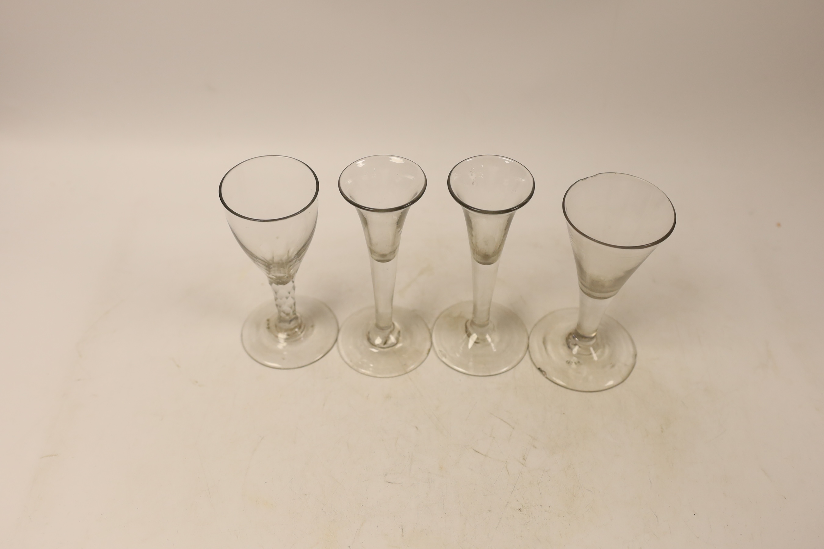 Three mid-18th century drawn trumpet drinking glasses, and a facet stem glass, tallest 13cm (4)